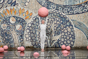 Young hairless girl with alopecia in white futuristic suit dancing outdoor smoothly holding pink...