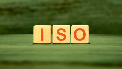 Concept of ISO. Quality management systems. ISO TEXT WRITTEN on wooden cubes on green saturated...