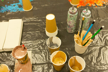 Epoxy resin different golden color cup for casting stabilizing wood, abstract art. Process of making accessory from resin. Mixing colorful resin chemical plastic cup. resin art paint