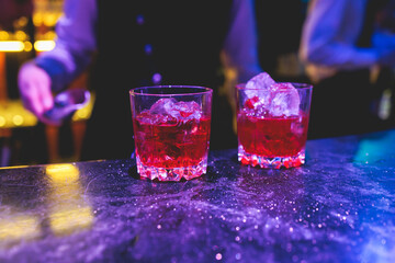 Bartender working, beautiful row line of different coloured liquor alcohol cocktails on a party in...