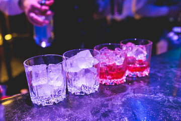 Bartender working, beautiful row line of different coloured liquor alcohol cocktails on a party in...