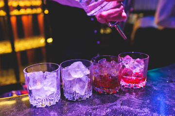 Bartender working, beautiful row line of different coloured liquor alcohol cocktails on a party in...