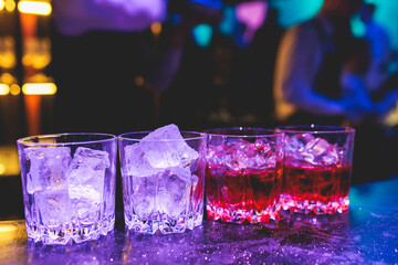 Bartender working, beautiful row line of different coloured liquor alcohol cocktails on a party in...