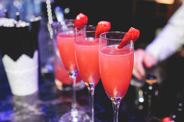 Bartender working, beautiful row line of different coloured liquor alcohol cocktails on a party in a bar, and others on catering banquet on event, barman mixing drinks and beverages in a club