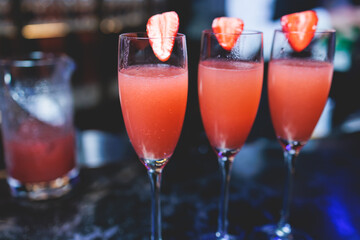 Bartender working, beautiful row line of different coloured liquor alcohol cocktails on a party in a bar, and others on catering banquet on event, barman mixing drinks and beverages in a club