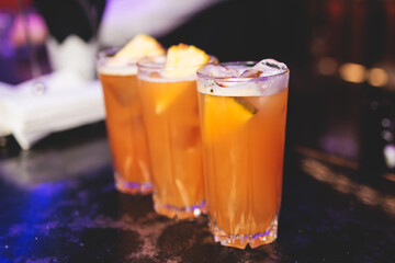 Bartender working, beautiful row line of different coloured liquor alcohol cocktails on a party in a bar, and others on catering banquet on event, barman mixing drinks and beverages in a club