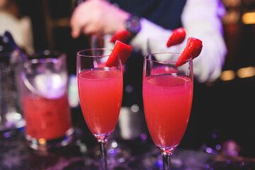 Bartender working, beautiful row line of different coloured liquor alcohol cocktails on a party in a bar, and others on catering banquet on event, barman mixing drinks and beverages in a club