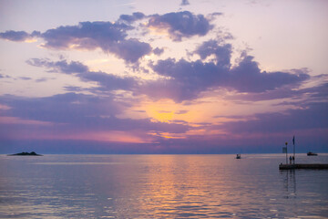 Fototapeta premium Beautiful sunset over calm sea, with vivid colors and clouds in the sky. Serenity and nature concept