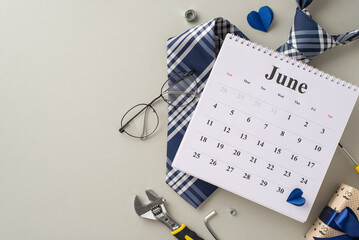 A themed photo for Father's Day showing a June calendar, tie, glasses, and tools spread around a heart on a neutral grey background