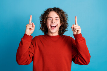 Photo of funky cool guy dressed red pullover pointing two fingers up emtpy space isolated blue...
