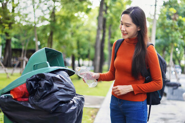 woman is throwing away trash and holding a bottle