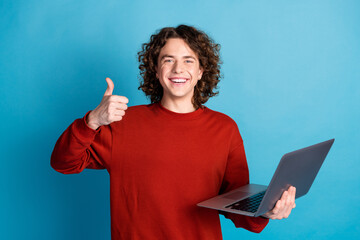 Photo of cheerful positive guy dressed red pullover working modern gadget showing thumb up isolated...