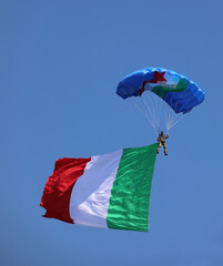 paratrooper with Italian flag on blue sky during National Alpini rally of Italian Military Corp