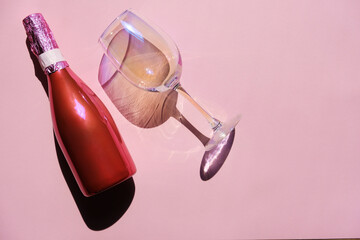 Holographic wine glass with pink wine bottle on pink background. Wine with a glass. Alcohol, summer vacation. Party.