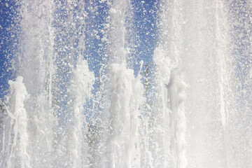 Water fountain splashing liquid against an electric blue sky