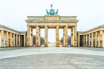The Brandenburg Gate stands majestically during dawn, its quiet presence dominating an empty...