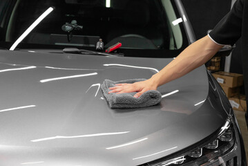 specialist in the salon waxes the client's car. Polishing the car body