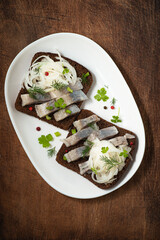 Herring dish: Smorrebrod with herring - toasted  rye  bread with spicy salted fish with pepper, pickled onions, dill. Dish of Scandinavian cuisine and the Baltic countries, traditional preservation.  