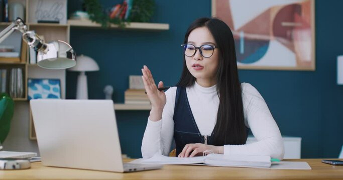 Cute Asian businesswoman or freelancer wearing glasses to use laptop. Hardworking woman participating in meeting with her investors or work colleagues. Discussing something for business improvement.