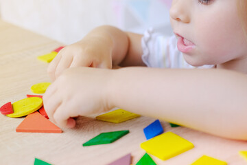 cute child, girl 3 years old plays with colored wooden geometric figures, counts details, concept...