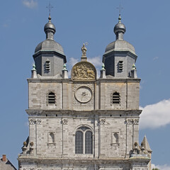  Detail of the front facade of the medieval Saint-Hubert Basilica on a sunny day with blue sky, wallonia , Belgium