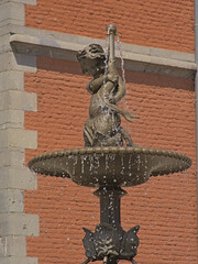 Decorative fountain wih depiciton of child and fish on Place de l`Abbeye square in Saint-Hubert 