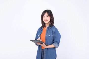 Asian woman wearing orange shirt and denim jean jacket is holding a tablet and a stylus against a...