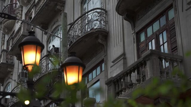 Facade of an old building with balconies in colonial style and illuminated street lamp in the foreground. El Conde street, Santo Domingo