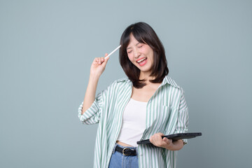 Fototapeta premium Portrait of young asian woman, teacher or student with digital tablet and pencil, writing, taking notes, doing her homework, standing over green background