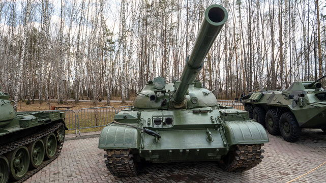 A large green tank is parked in front of a forest