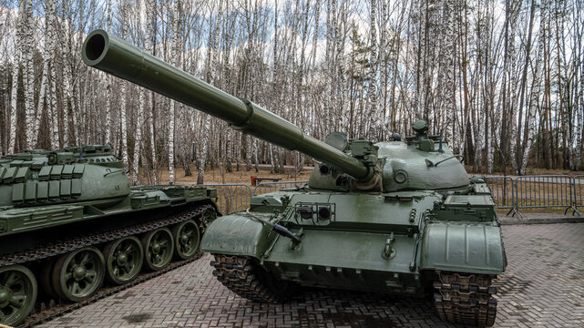 A large green tank is parked in front of a forest