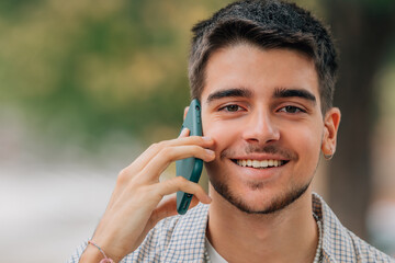 portrait of bearded young man talking on mobile phone in the street
