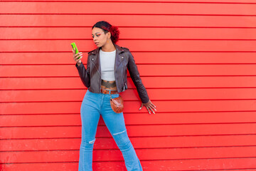 urban girl with mobile phone and red wall background