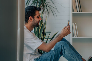 young man with mobile phone at home with copy-space