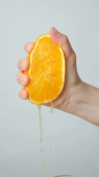 The process of squeezing orange juice from half a fresh orange, slow motion vertical shooting.