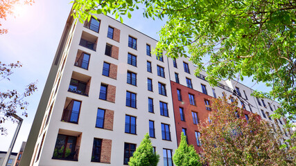 Modern residential building with new apartments in a green residential area. Eco architecture. Green tree and new apartment building. The harmony of nature and modernity.
