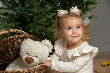 A funny little girl takes a fluffy teddy bear out of the basket in the Christmas room.