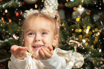 Happy Little girl against the background of a Christmas tree and golden confetti.