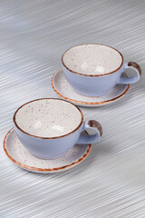 Ceramic clay cups and saucers on a gray background.