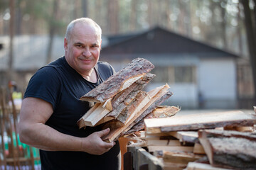 An elderly man prepares firewood for the winter.