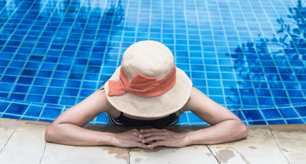 Woman with beach hat relaxing in poolside