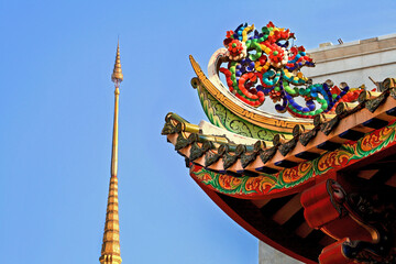 Colorful ornate Chinese and Thai style roof eve detail in the blue sky background