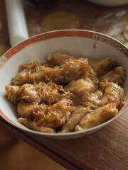 Vertical close-up of Ukrainian varenyky, dumplings akin to Italian ravioli, with caramelized onions on top in a plate on a kitchen table.