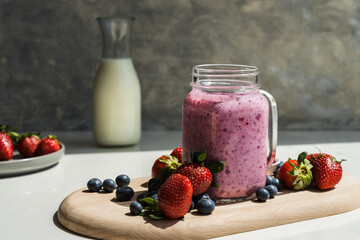 healthy red berry smoothie in a glass jar on a grey background
