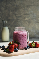 healthy red berry smoothie in a glass jar on a grey background