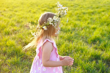 happy romantic girl 4 years old, floral crown, wreath adorns head Cheerful child playing on green...