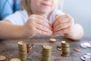 small child makes roof over metal coins, kid puts euro union money, protection concept, insurance...