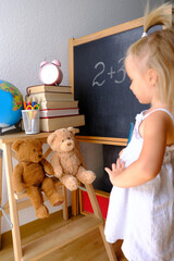 child, blonde girl plays school, small teacher teaches lesson, student home office, alarm clock,...