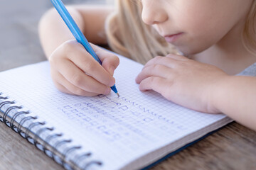 child's hand writes with pen in notebook, practicing handwriting for preschooler, hand development,...