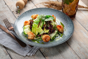 Salad with grilled shrimp and fresh green vegetables, spinach leaves and zucchini in blue plate. Healthy seafood salad with pesto sauce, close up - Powered by Adobe